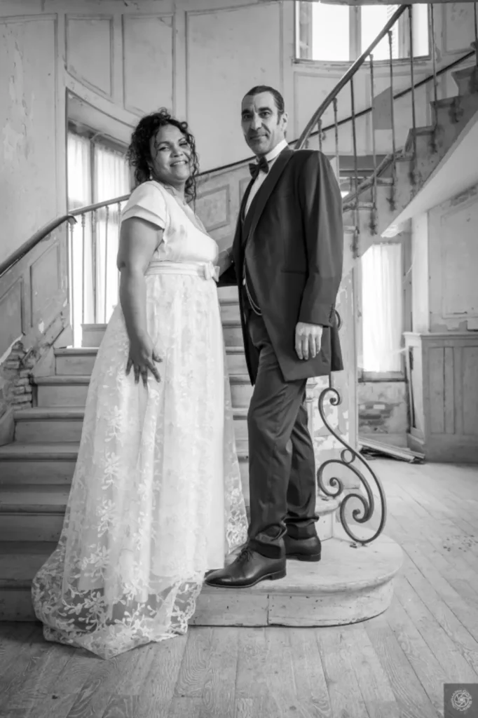 Couple de mariés posant dans un lieu de réception, photo en noir et blanc